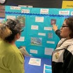 Student showing a visitor her exhibition