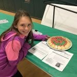 student posing next to the food she made for exhibition
